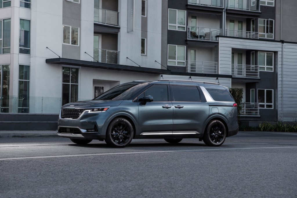 A turquoise 2022 Kia Carnival driving down a city road