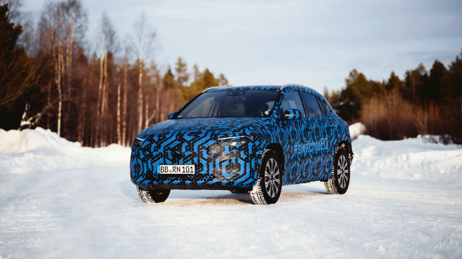 A camo-wrapped 2022 Mercedes-Benz EQA during winter testing on a snow-covered road