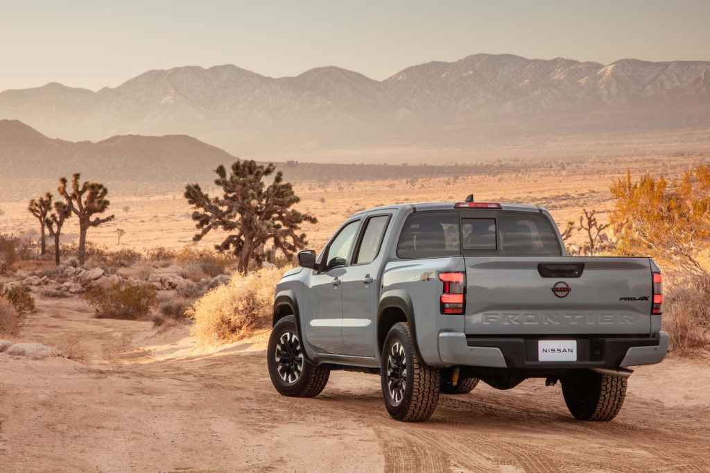 a rear quarter view of the 2022 nissan frontier driving off into the dessert.