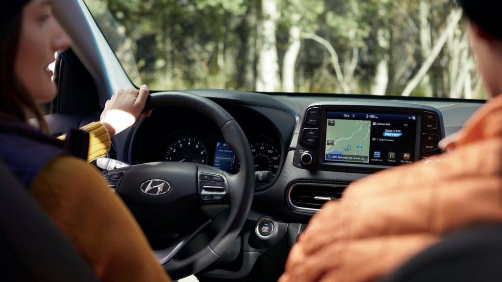 a picture of a woman driving the 2021 hyundai kona from the view of a rear seat passenger shows how navigation in the Kona is not a problem