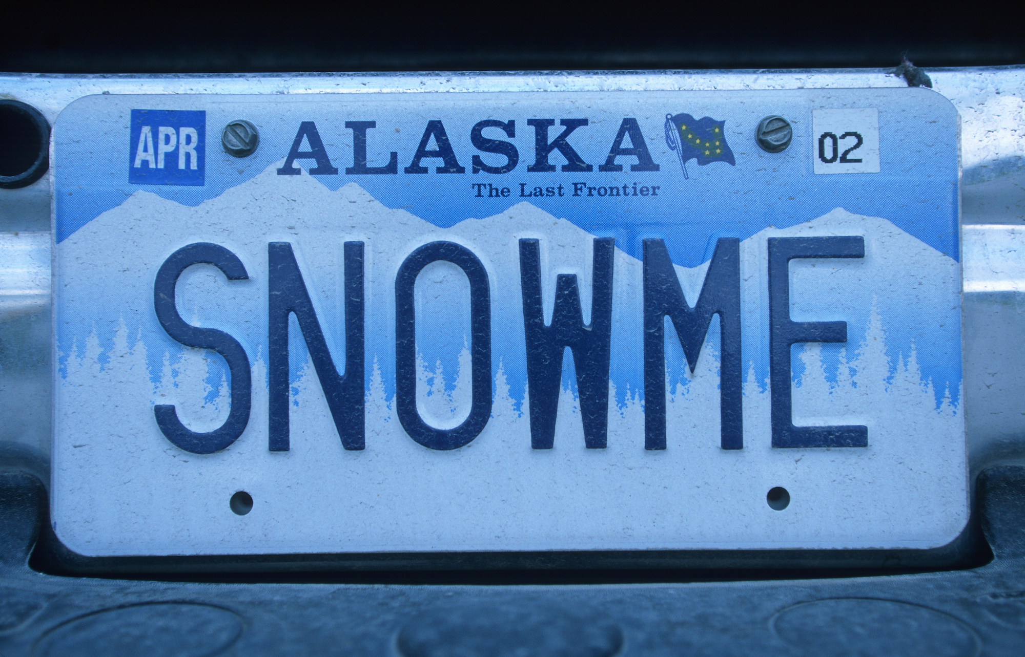 A blue and white Alaska vanity license plate reading, "Snow me"