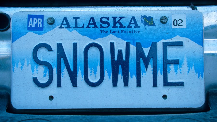 A blue and white Alaska vanity license plate reading, "Snow me"