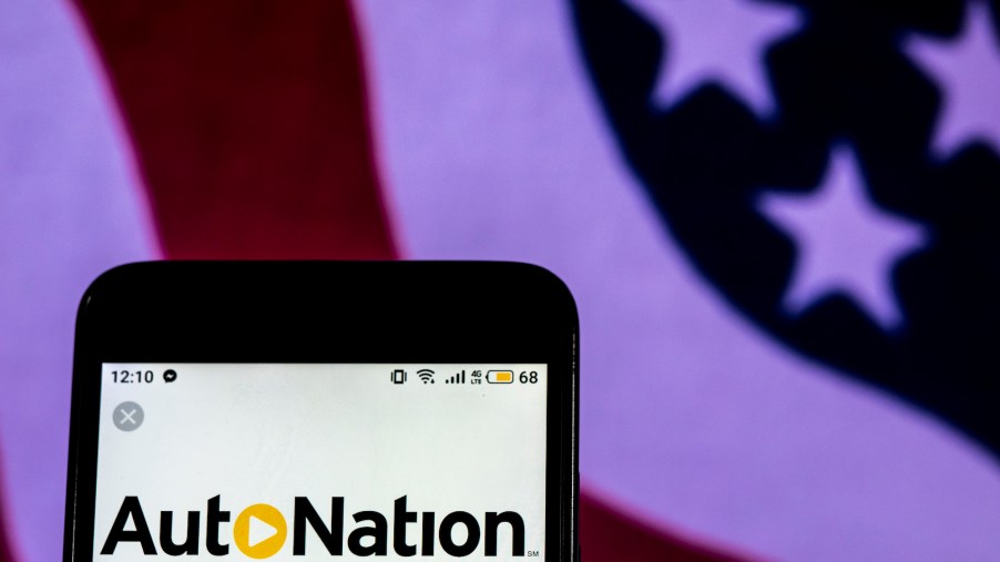 The AutoNation logo displayed on a smartphone with an American flag in the background