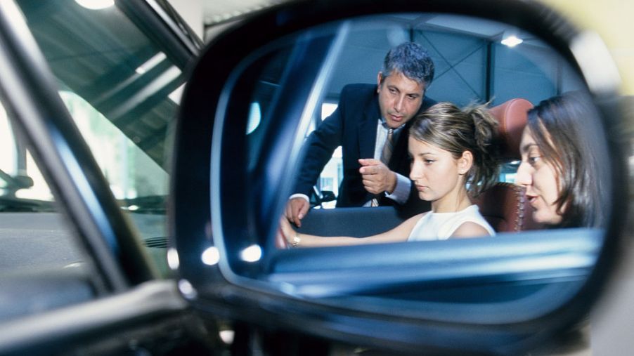 mirror reflection of woman being sold car by salesman