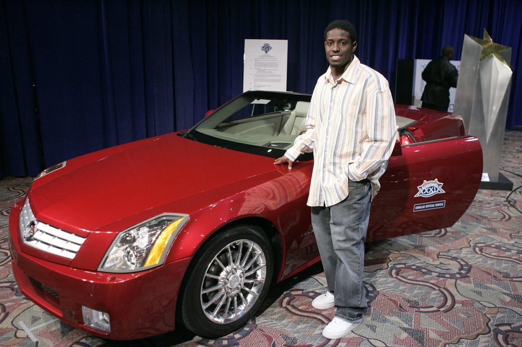 Deion Branch standing next to his Super Bowl MVP car, a red Cadillac XLR