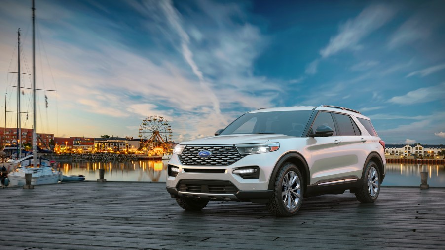 A white 2021 Ford Explorer sits near the water with a beautiful sunrise behind