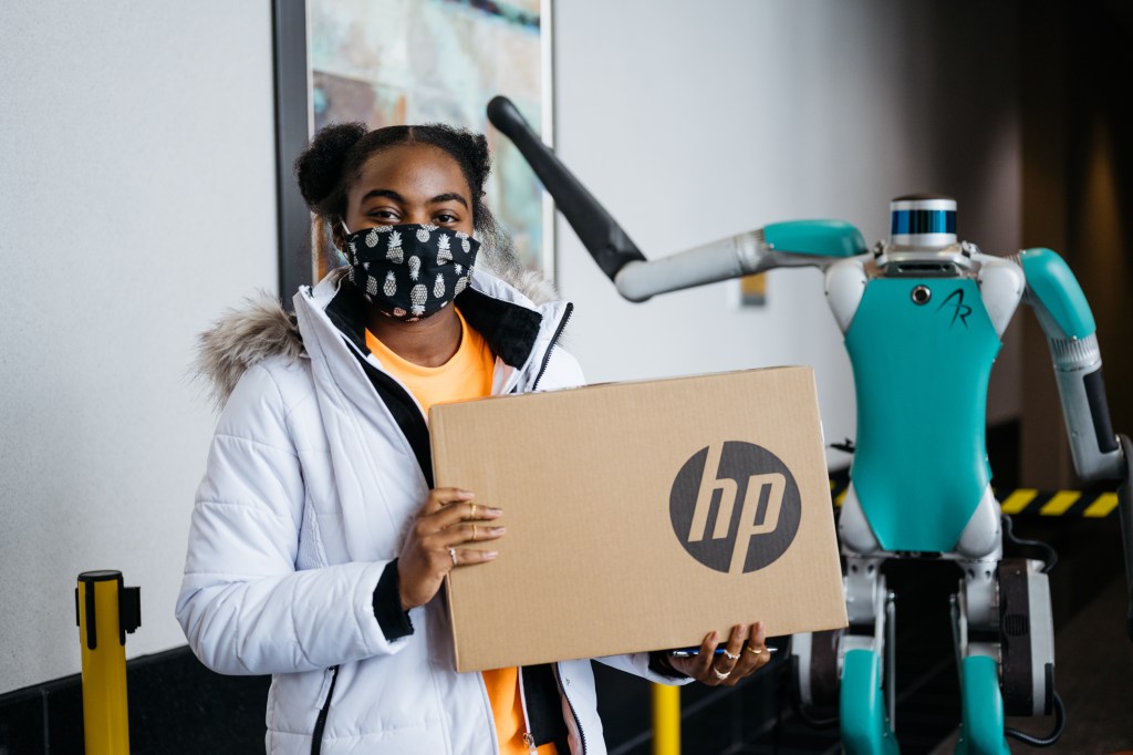 A young girl at the Girls in Engineering Academy holds a laptop box donated by Ford