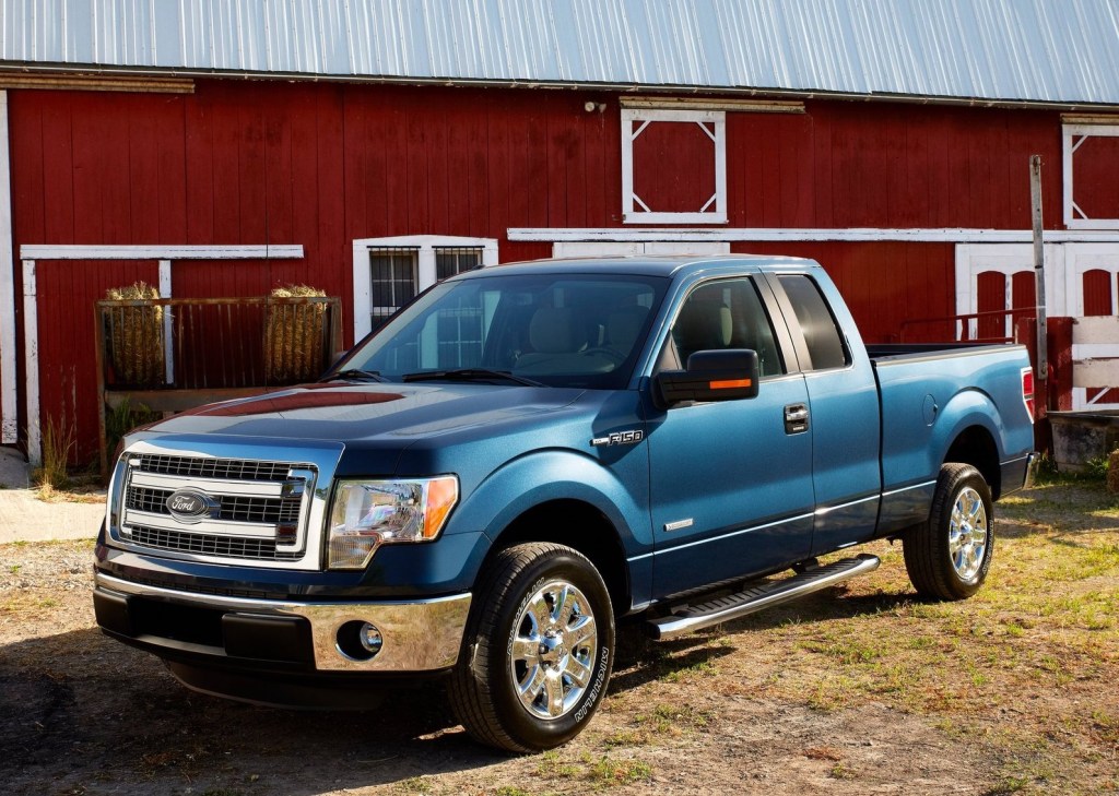 a blue 2013 Ford F-150 poses in front of a barn