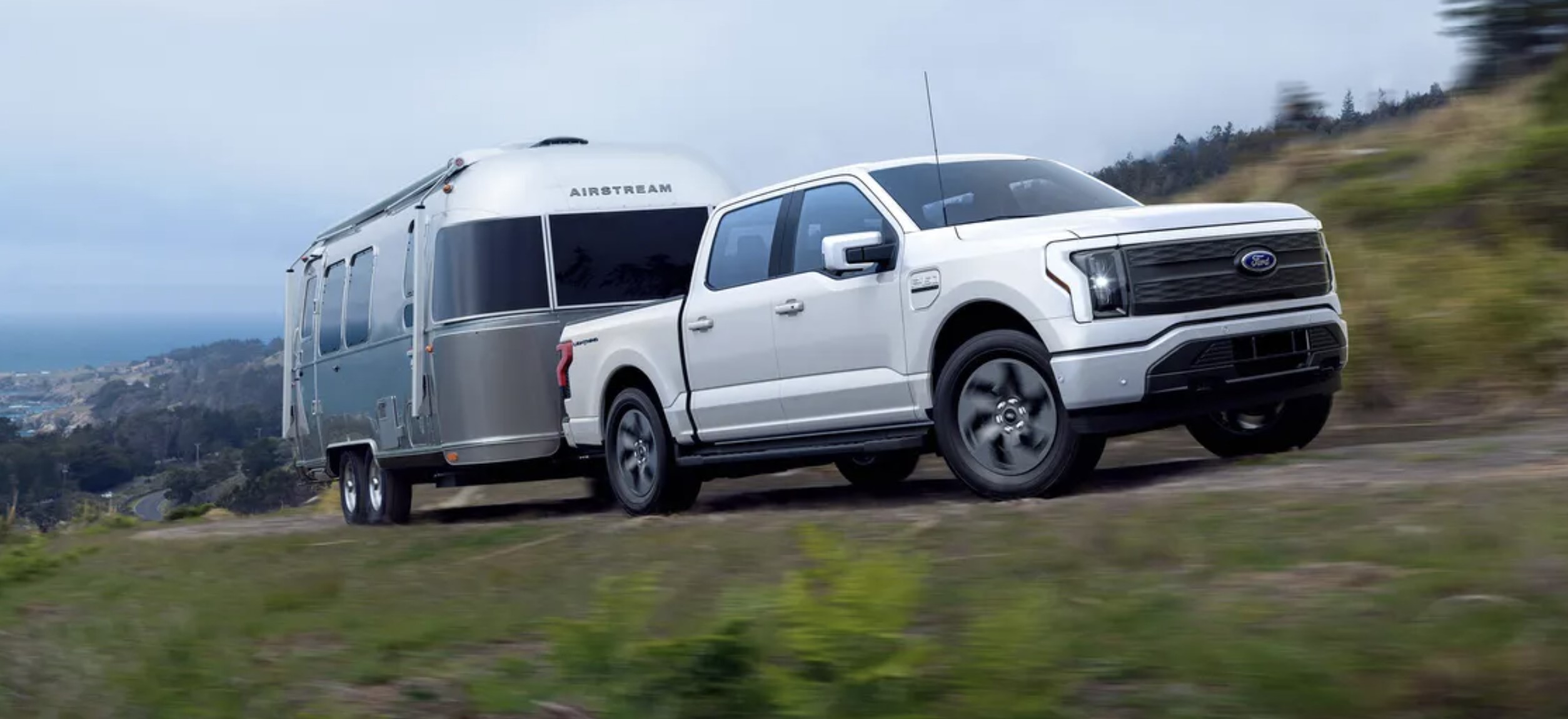 The 2022 Ford F-150 Lightning towing an RV up a curvy road