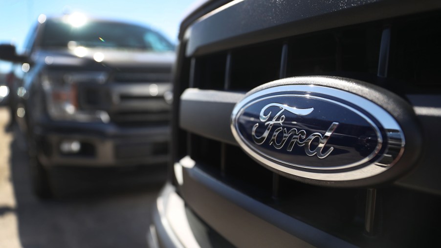 Ford F-150 trucks sit in the sun on at a dealership.