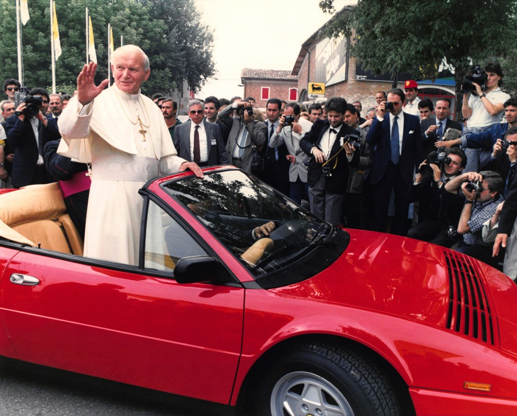 An image of John Paul II riding on a convertible Ferrari.