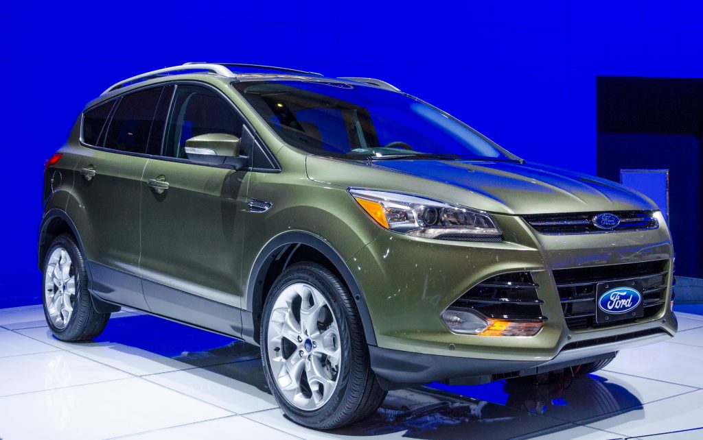 A green 2013 Ford Escape on display in front of a blue wall