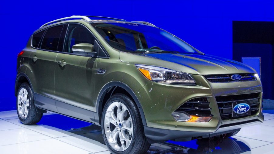 A green 2013 Ford Escape on display in front of a blue wall
