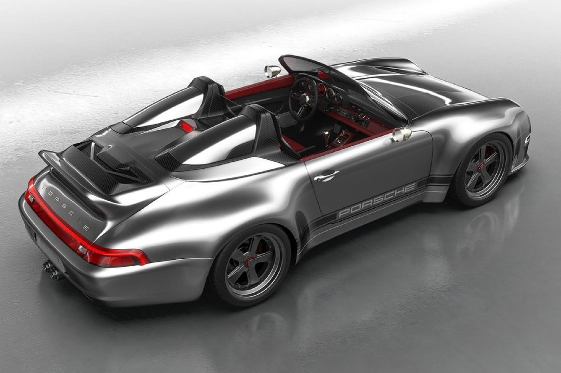 The overhead rear 3/4 view of a silver Gunther Werks 993 911 Speedster with a red interior