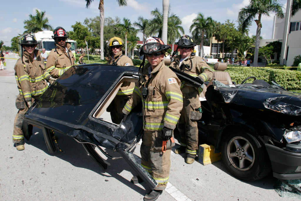 Jaws of life and car top with firefighters posing