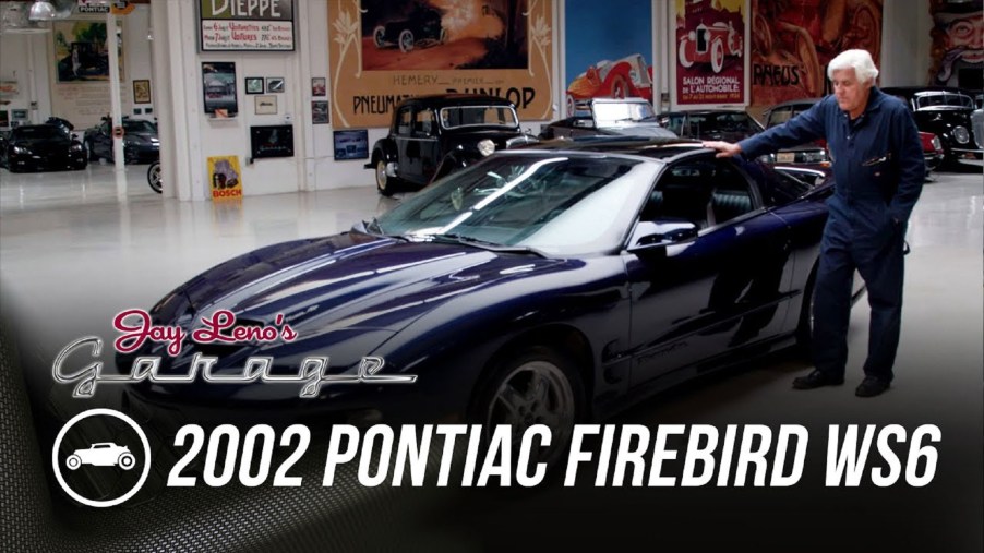 Jay Leno with his blue 2002 Pontiac Firebird Trans Am WS6 in his garage