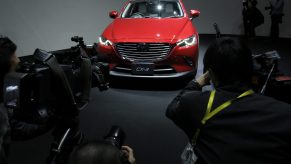 Members of the media take photographs and film videos of Mazda Motor Corp.'s new CX-3 compact crossover sport-utility vehicle (SUV) on display during a news conference in Tokyo, Japan