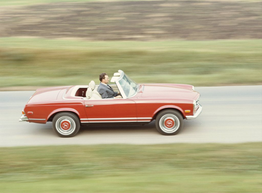 An image of a Mercedes-Benz 230 SL driving down the road.