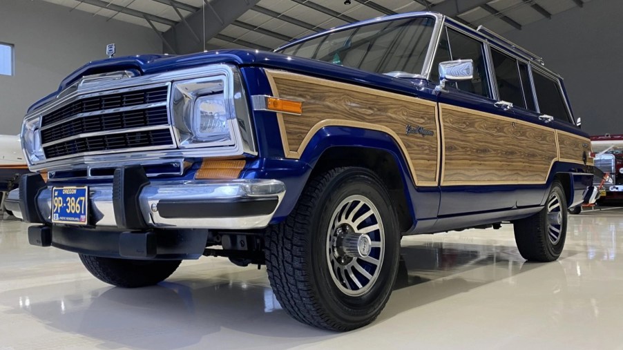 A low-angle front 3/4 view of a modified blue 1991 Jeep Grand Wagoneer in a hanger