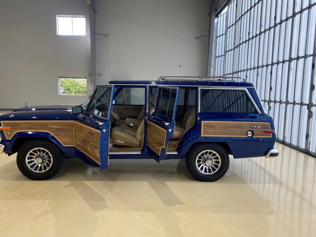 The side view of a modified blue 1991 Jeep Grand Wagoneer with its doors open