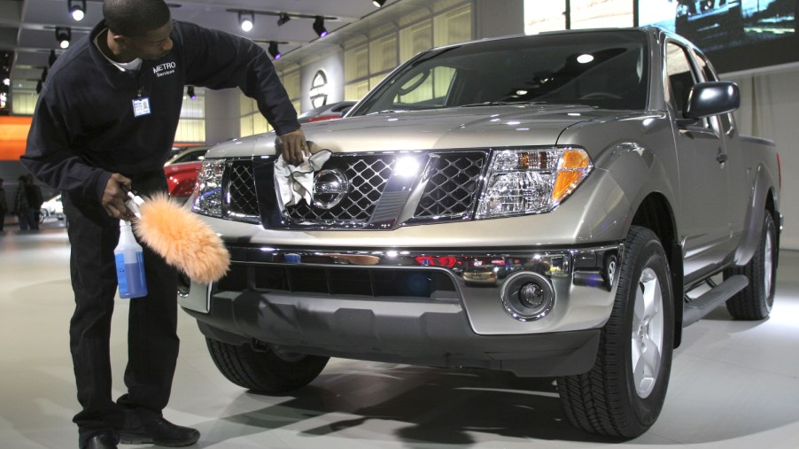 A worker polishes a silver Nissan Frontier sits on display