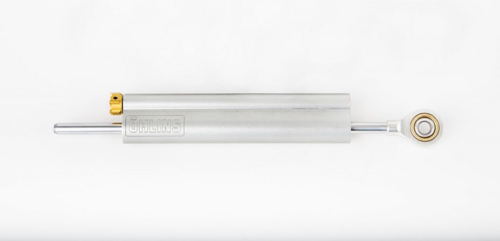 A silver adjustable Ohlins motorcycle steering damper with gold knobs