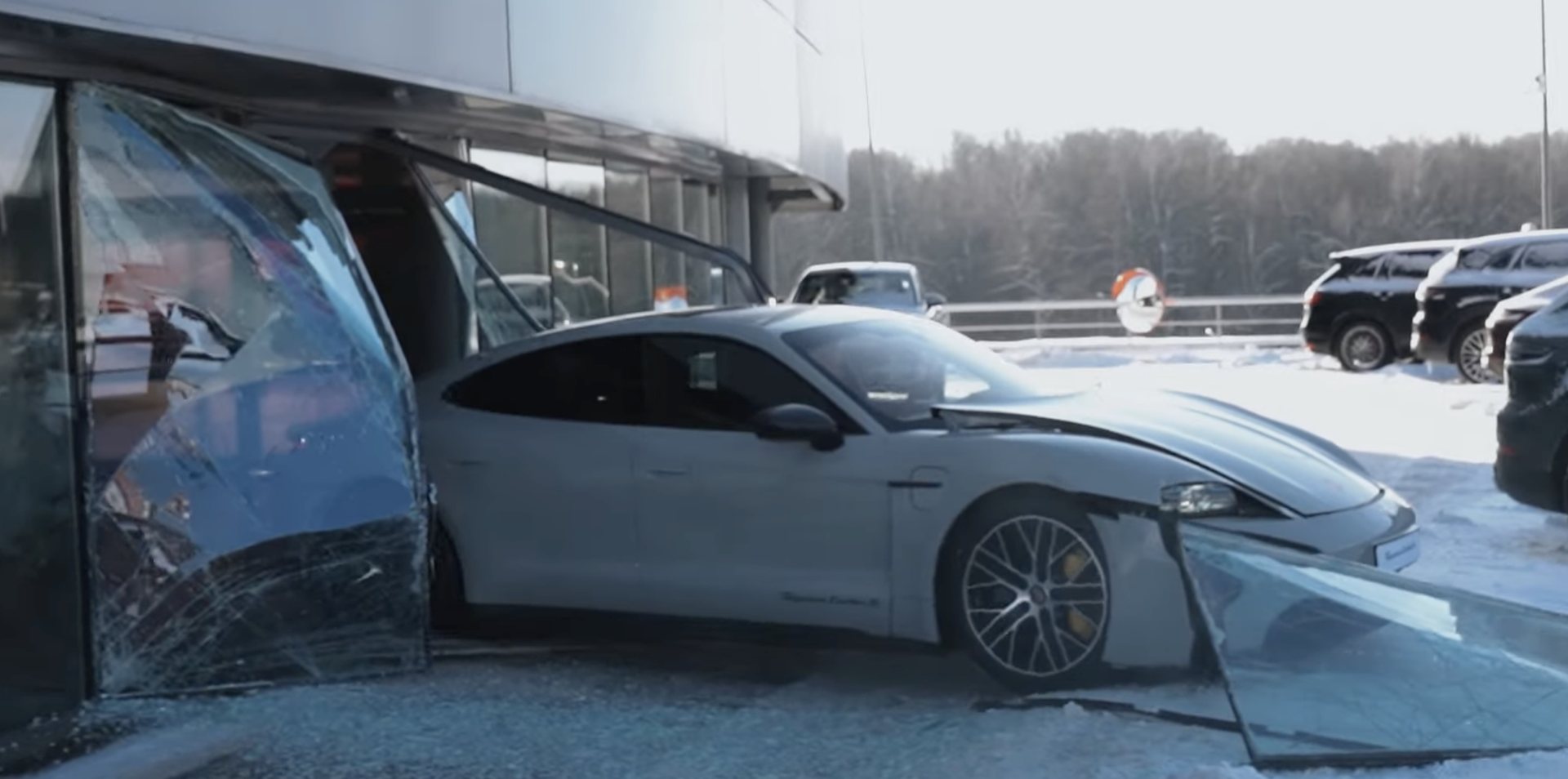 An image of a 2021 Porsche Taycan Turbo S slamming through the windows of a dealership.