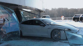 An image of a 2021 Porsche Taycan Turbo S slamming through the windows of a dealership.