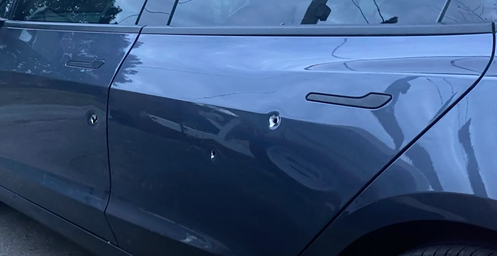 An image of a Tesla Model 3's door showing bullet holes.