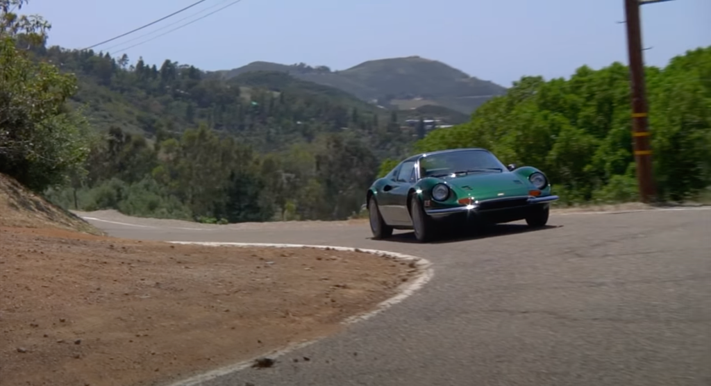 An image of a Ferrari Dino rolling down the road.