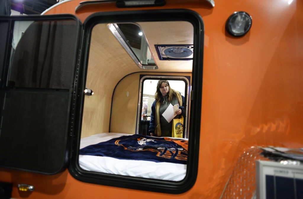 A woman takes a look inside of a teardrop camper at an RV show