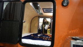 A woman takes a look inside of a teardrop camper at an RV show