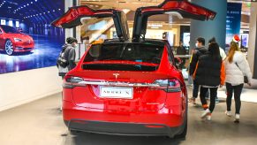 Customers watch a Model X vehicle at a Tesla flagship store