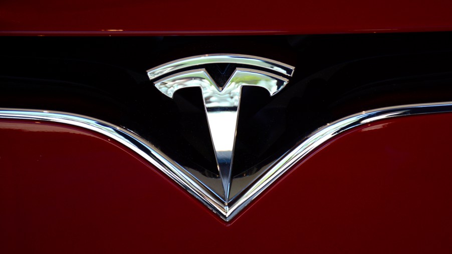 The Tesla logo on the nose of a red electric sedan