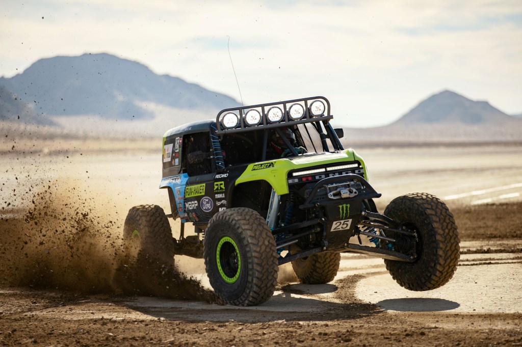 The black-and-green No. 25 2021 Ford Bronco 4400 racer slides through sand