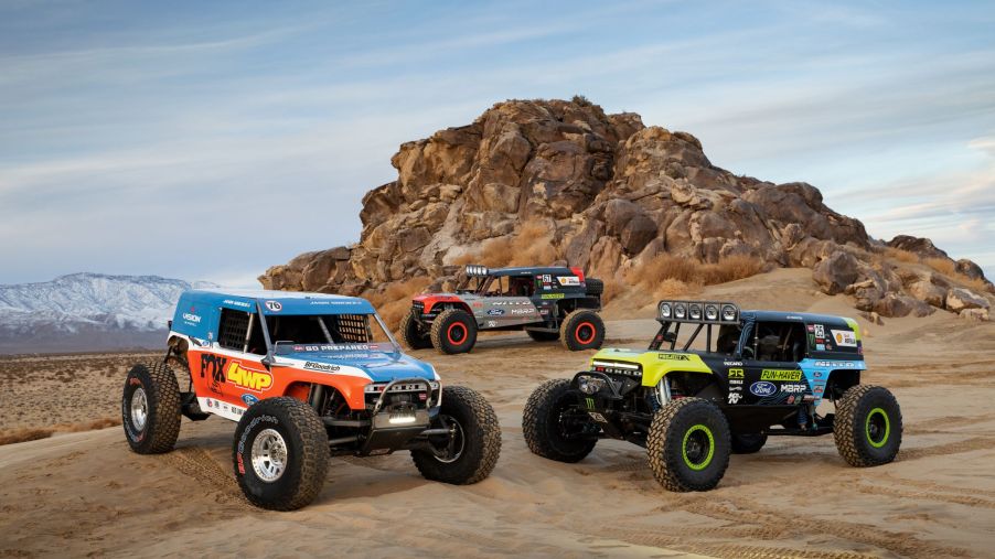 The three 2021 Ford Bronco 4400 King of the Hammers racers gathered around a desert rock formation