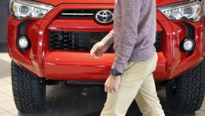 A person walks by a red Toyota 4Runner in a dealership