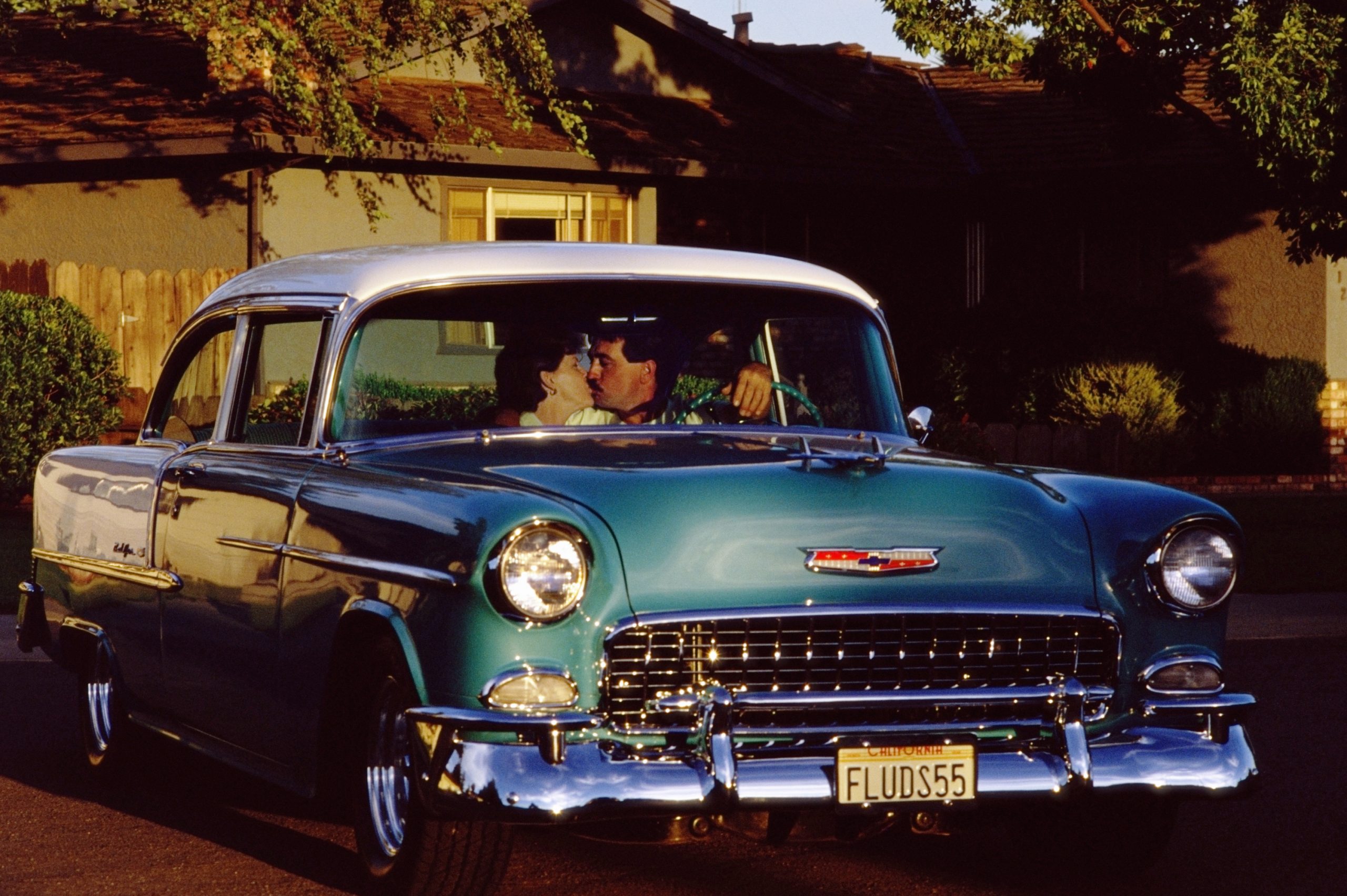 A couple kissing during a car date in a blue vintage car