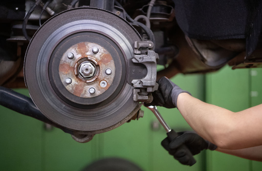 A car mechanic works on the brake disc of a car 