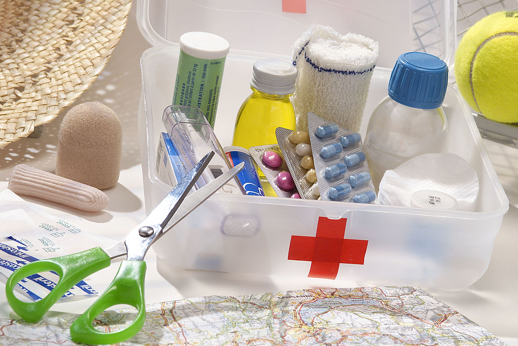 A basic first aid kit featuring bandaids, scissors, and basic medicine. 