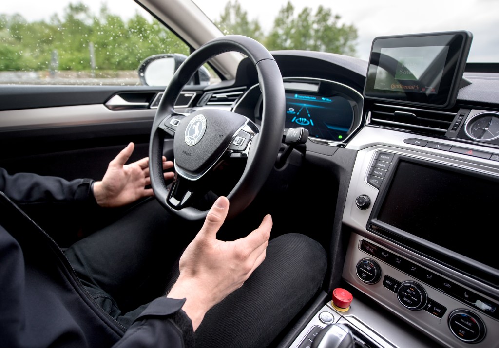 a man removes his hands from the steering wheel when driving.