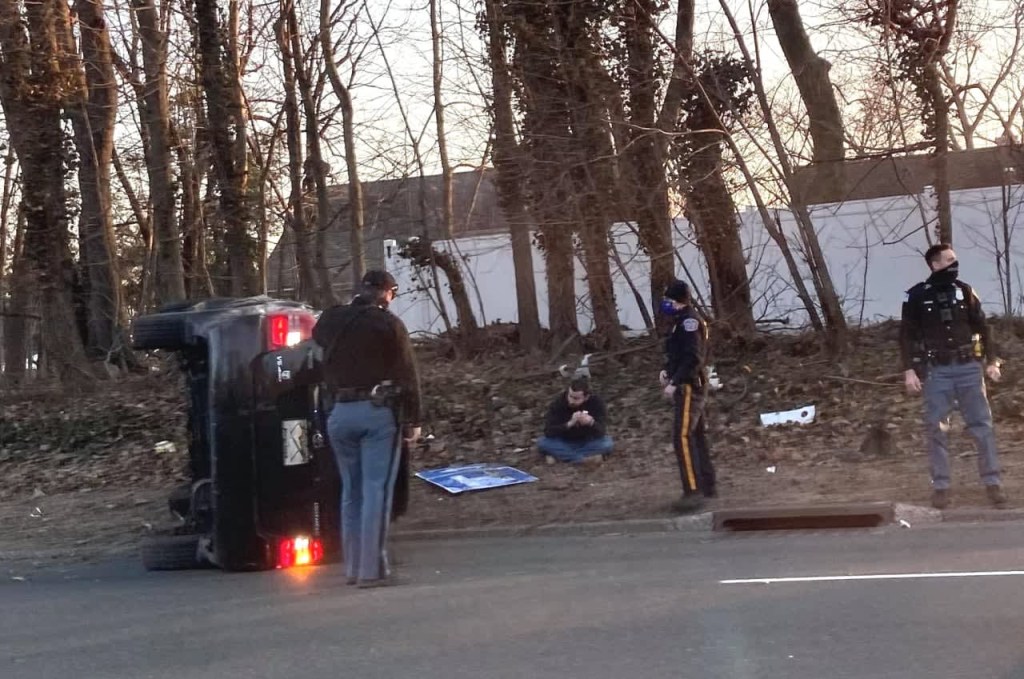 A Toyota 4Runner on its side after flipping around a curve.