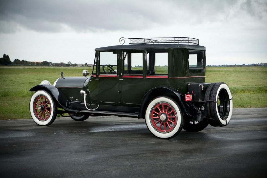 The side 3/4 view of a dark-green 1915 Crane-Simplex Model 5 Sport Berline parked on a runway