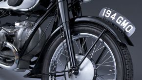 The front half of a black 1936 BMW R 5 motorcycle, showing the forks and the front drum brake assembly