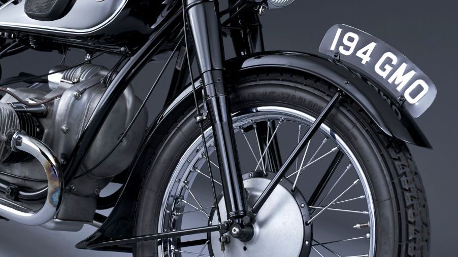 The front half of a black 1936 BMW R 5 motorcycle, showing the forks and the front drum brake assembly