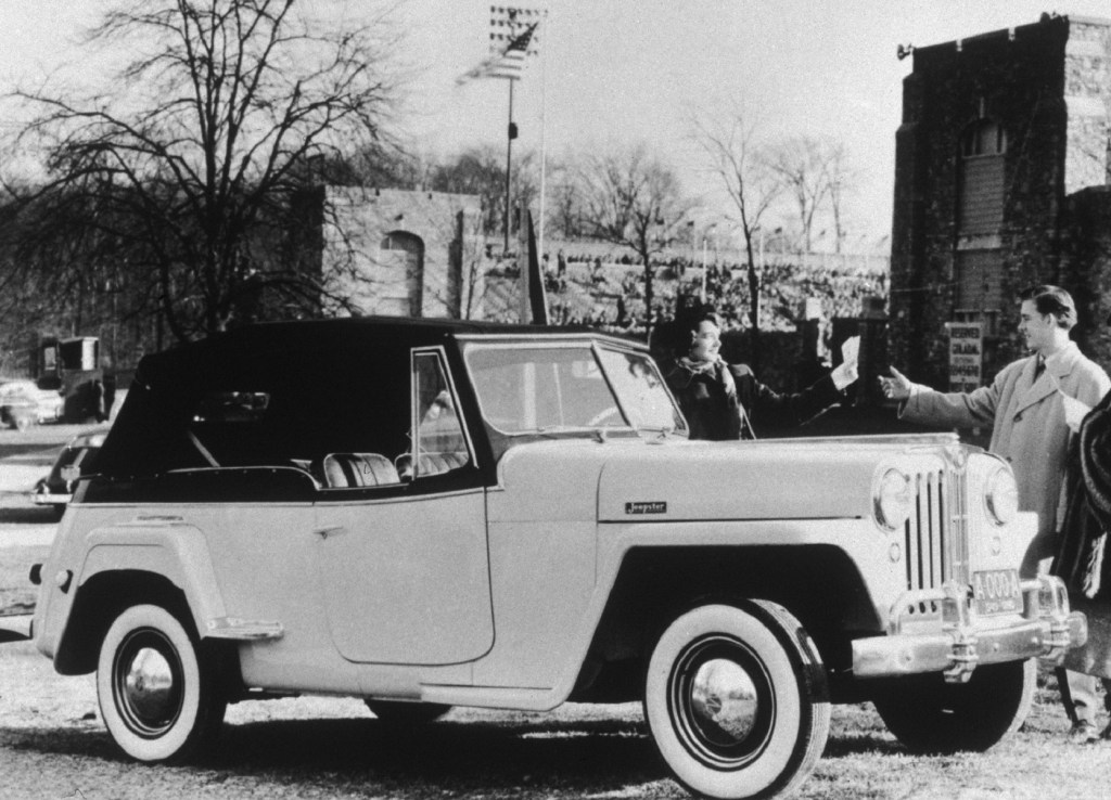 A black-and-white photo of a man and a woman with a 1948 Jeepster
