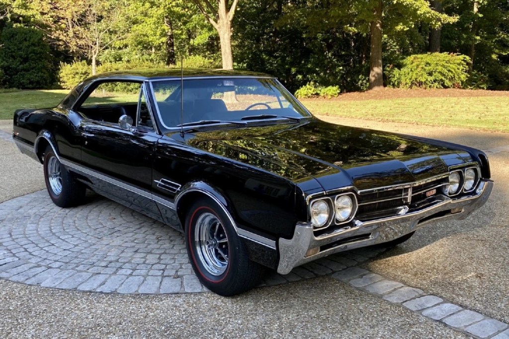 A black 1966 Oldsmobile 442 in a stone-lined driveway