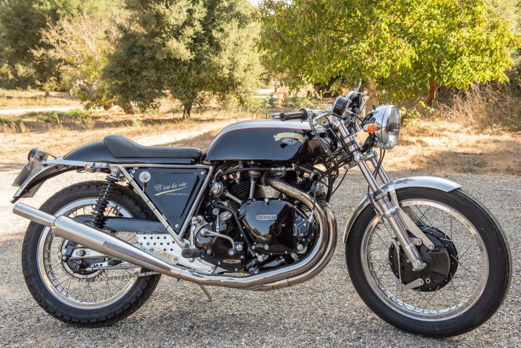 The side view of a black-and-silver 1968 Egli-Vincent by Godet on a sunlit gravel driveway