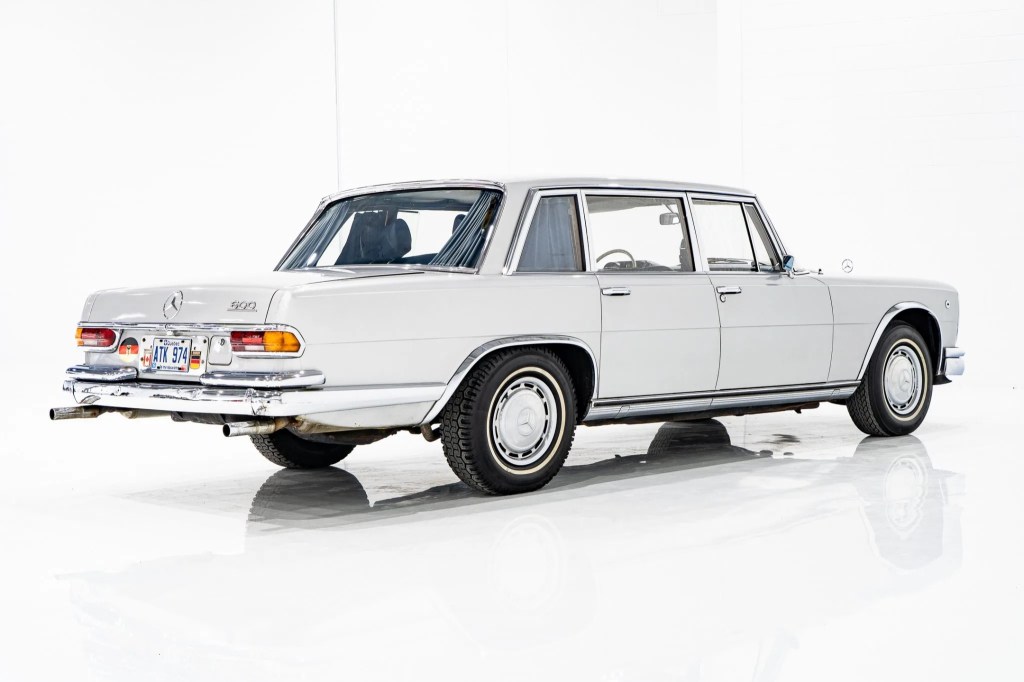 The rear 3/4 view of a white 1969 Mercedes 600 in a white studio