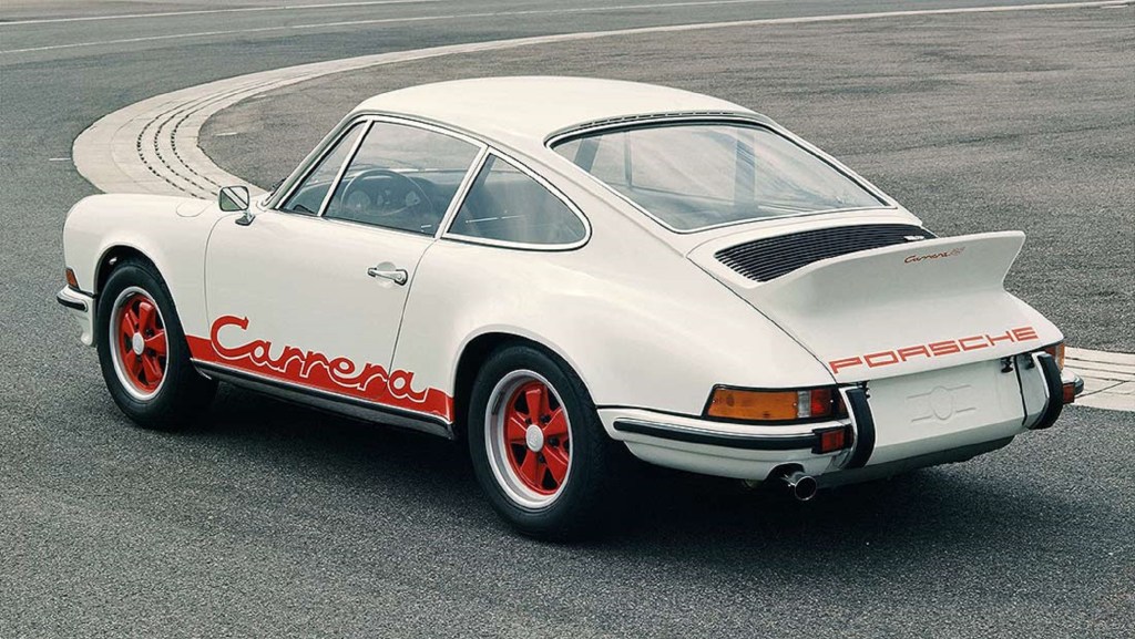 The rear 3/4 view of a white-with-red-graphics 1973 Porsche 911 Carrera 2.7 RS on a racetrack